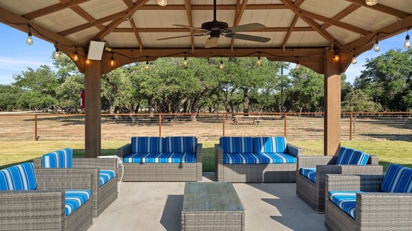 An outdoor patio with wicker furniture and a ceiling fan.