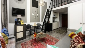 A modern living room with a grey sofa, a red patterned rug, and a staircase leading to an upper level. - Native Apartments Studencka 25 (Kraków)