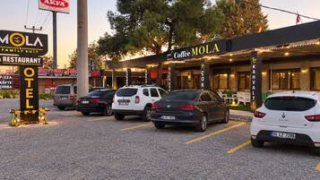 A parking lot with several cars, a coffee shop named 'Coffee MOLA,' and a sign for 'AKFA.'