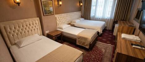 Habitación de hotel con dos camas, un escritorio de madera, televisión y una alfombra roja estampada.