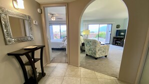 A hallway leading to a living room with a view, a ceiling fan, a table, and a mirror. - Green Valley Casita - View ! (Green Valley)