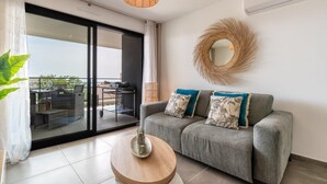 A modern living room with a grey sofa, a round mirror, and a hanging light fixture. - Dieu Nérée & its sea view (Sète)