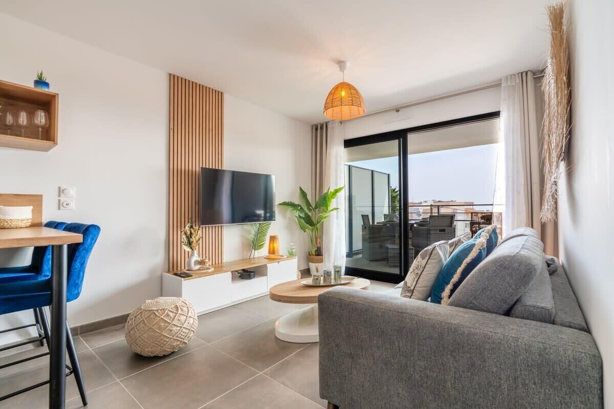 Un salon moderne comprenant un canapé, un téléviseur, un coin repas et un balcon avec vue.