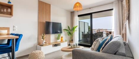 Un salon moderne comprenant un canapé, un téléviseur, un coin repas et un balcon avec vue.