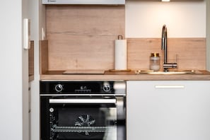 A kitchen with a wooden countertop, a stainless steel range hood, a sink with a faucet, and an oven.