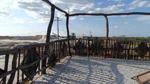 A tiled deck with a wooden fence, a clear sky, and distant dunes. - Del mar vendra (Manaure)