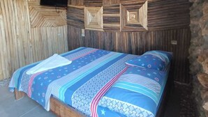 A room with a wooden slat ceiling, a bed with patterned bedding, and a mounted television. - Del mar vendra (Manaure)