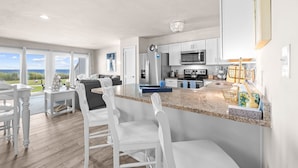 Cocina moderna con armarios blancos, encimera de granito y vistas al exterior.