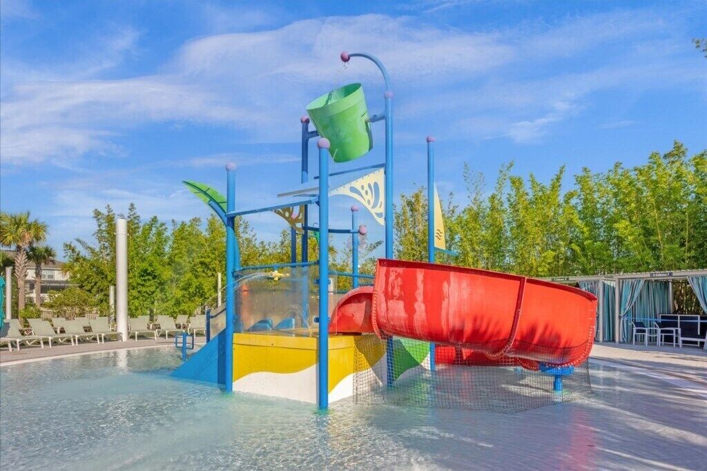 Ein Wasserpark mit Wasserrutsche, Schwimmbecken und Liegebereich mit Stühlen.
