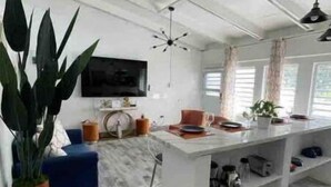 Eine moderne Küche mit einer weißen Kochinsel, einem blauen Sofa und einer großen Kübelpflanze.