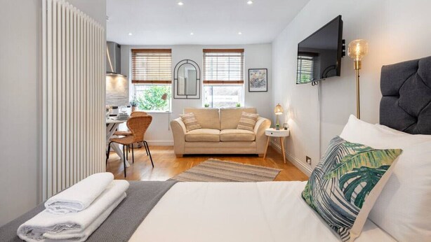 A modern bedroom with a bed, a sofa, a desk, and a TV.