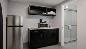 Una cocina moderna con un refrigerador de acero inoxidable, un microondas y una cafetera sobre la encimera.