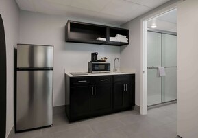 A modern kitchen with a stainless steel refrigerator, a microwave, and a coffee maker on the countertop.