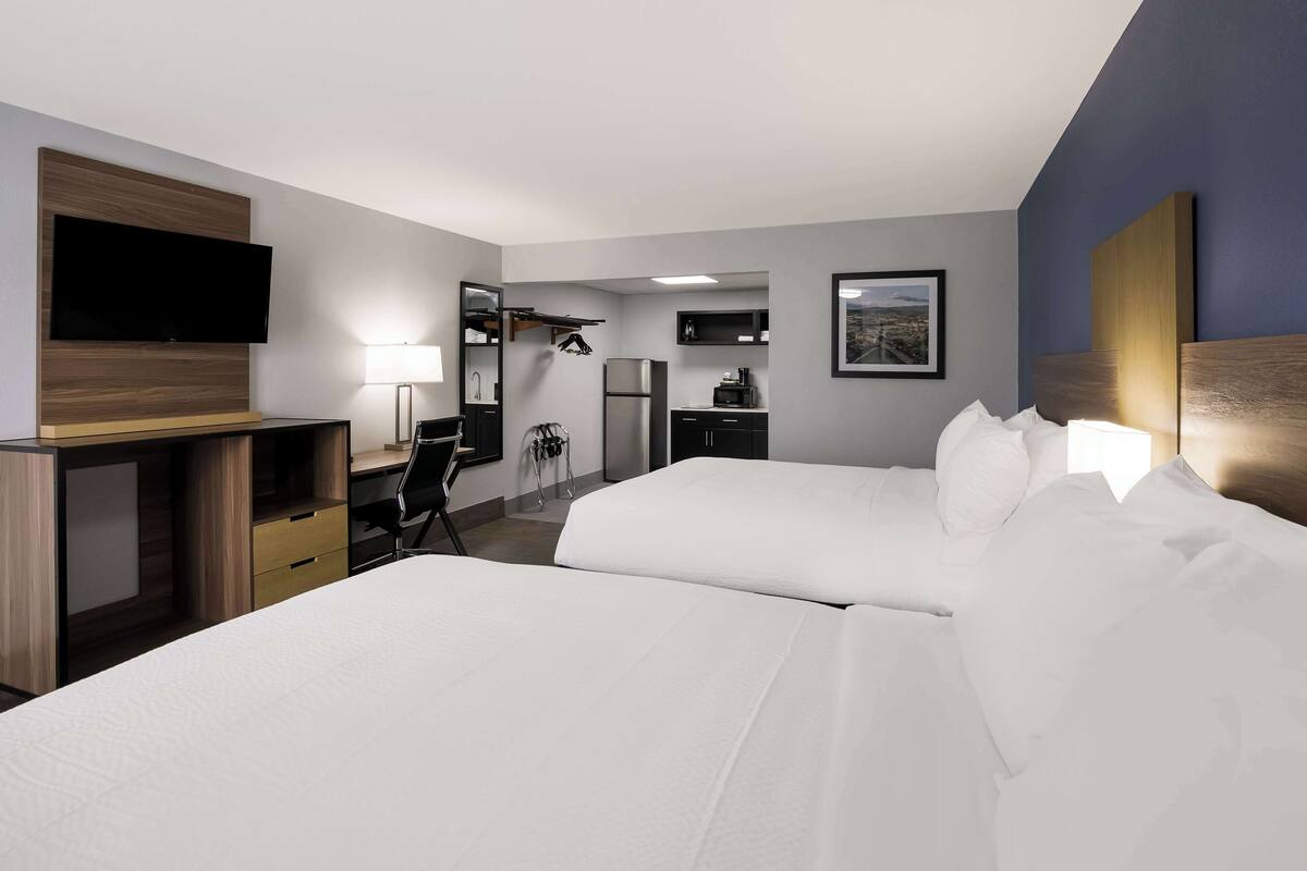 Hotelkamer met twee bedden, een bureau, een stoel, een televisie, een lamp en een koelkast.