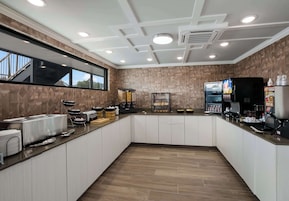 A modern kitchen with a central island, built-in appliances, and a large window.