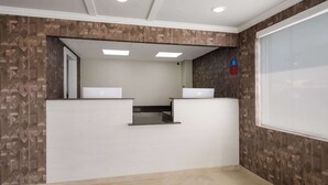 Un área de recepción con diseño moderno, que presenta una pared con motivos, una recepción y un ventanal grande.