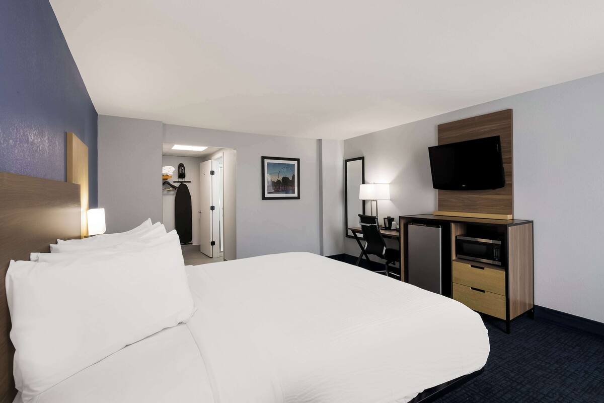 Een hotelkamer met een groot bed, een bureau met een computer, een televisie en een magnetron.