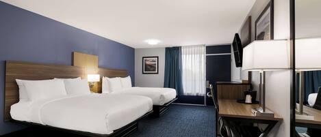 A hotel room with two beds, a desk, a chair, a TV, and a window with curtains.