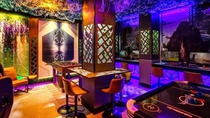 Una stanza con un tavolo da calcio, un angolo bar e una parete decorata con una scena naturale.