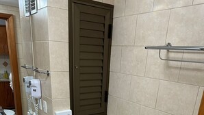 A small, modern bathroom with a toilet, bidet, and sink. There is a towel rack above the sink and a small trash bin next to the toilet.