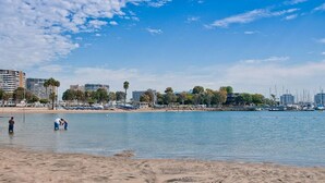 A beach with people in the water, a marina with boats, and buildings in the background. - Trendy Getaway | Hot Tub | 20 mins to Disney (Long Beach)