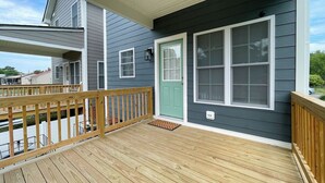 A wooden deck with a green door and white-framed windows.