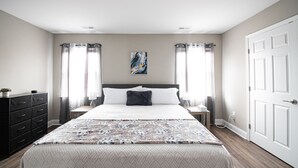 A bedroom with a bed, nightstands, a dresser, and a door.