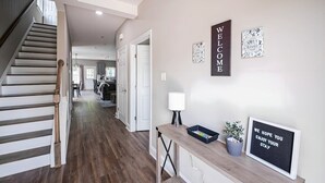 A modern interior with a staircase, a welcoming sign, and a desk with a lamp and a framed message.