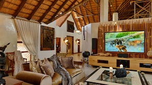 Een ruime woonkamer met een hoge plafond, een grote flatscreen-tv, comfortabele zithoek en een rustieke inrichting.