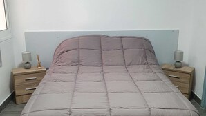 Een slaapkamer met een bed, twee nachtkastjes, een kunstwerk aan de muur en een raam.