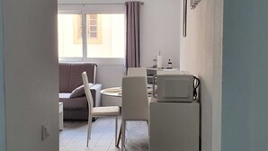 Een knus woongedeelte met een kitchenette, een eethoek en een bank.