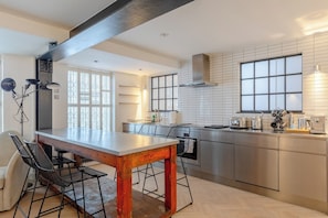 A modern kitchen with a dining area, featuring a large island, stainless steel appliances, and a view of the city.
