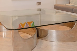 A modern living room with a glass coffee table, a sofa, and a wooden floor.