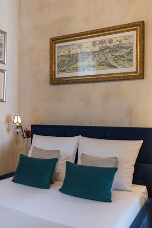 A neatly made bed with two pillows, a wall-mounted picture, and a wall-mounted lamp. - Native Apartments Dunajewskiego 2 (Kraków)
