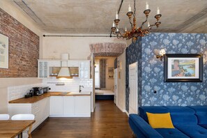 A modern kitchen with white cabinetry, a wooden countertop, and a brick wall. - Native Apartments Dunajewskiego 2 (Kraków)