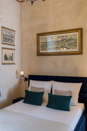 A hotel room with a bed, two framed pictures on the wall, and a nightstand with a lamp.