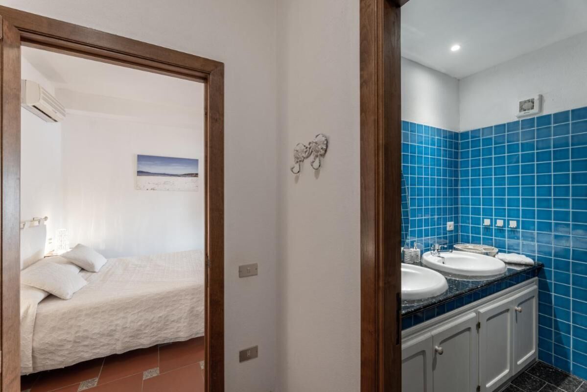 Ein Schlafzimmer mit einem Bett, ein Badezimmer mit blauen Fliesen und einem Bild an der Wand.