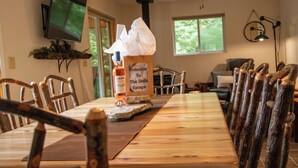 Una mesa de madera para comer con una botella de aceite de oliva y un cartel de bienvenida.