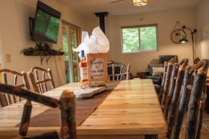 A wooden dining table with a bottle of olive oil and a welcome sign.