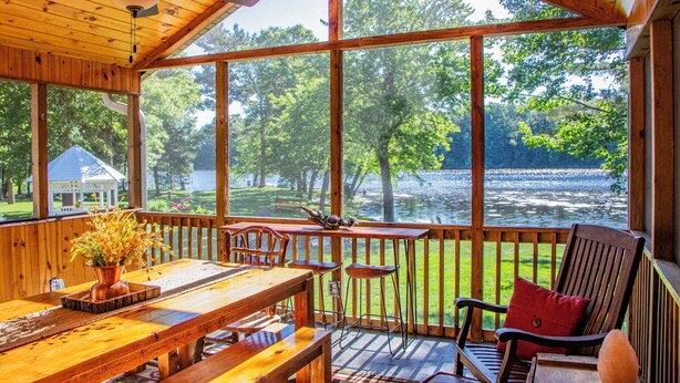 Una terraza de madera con mesa y sillas, con vista a un lago.