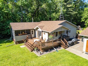 A two-story house with a covered porch, a screened-in room, and a small deck area. - Welcome to Dells Escape: A Historic Getaway on Dells Mill Pond (Augusta)