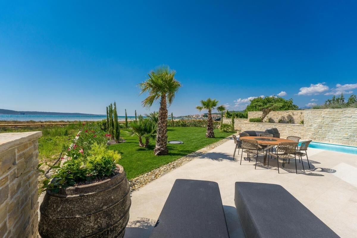 A patio with a pool, outdoor furniture, and a view of the sea.