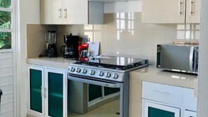 Une cuisine compacte équipée d’une cuisinière intégrée, d’un four à micro-ondes et d’une machine à café.