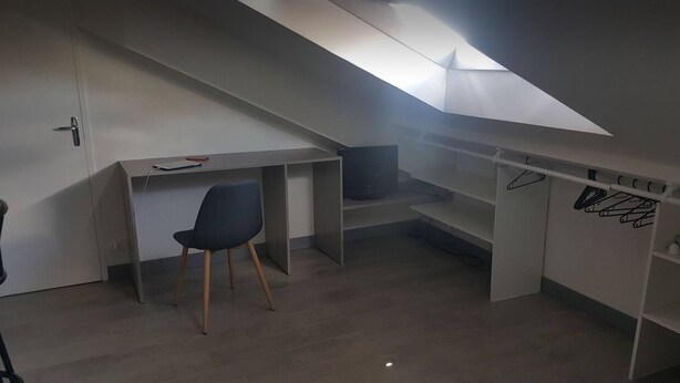 Una habitación pequeña con escritorio, silla y televisor.