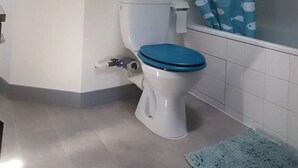 Un baño con inodoro, cortina de ducha azul y tapete de baño azul.