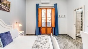 Una habitación de hotel con cama, mesita de noche, lámpara, ventana con cortinas y aire acondicionado.