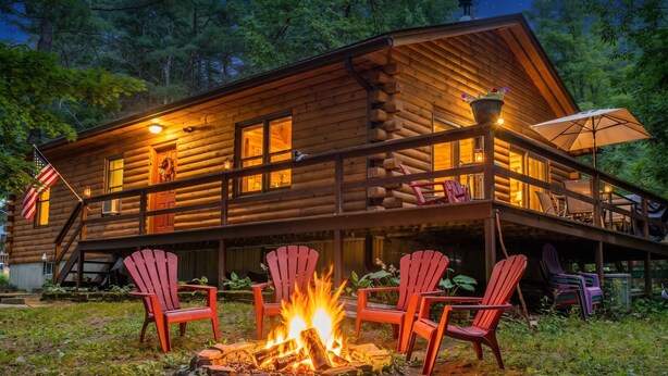 Une cabane en rondins dotée d’une terrasse, de coins salon extérieurs et d’un foyer.