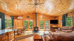 L’intérieur d’un chalet en bois comprend une cheminée, un coin repas et un espace détente.