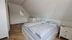 A bedroom with a bed, nightstands, a dresser, and a small window.