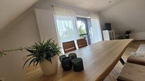 A dining area with a wooden table, chairs, and potted plants.
